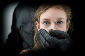Man's Hand Covering Mouth Of Scared Young Girl.